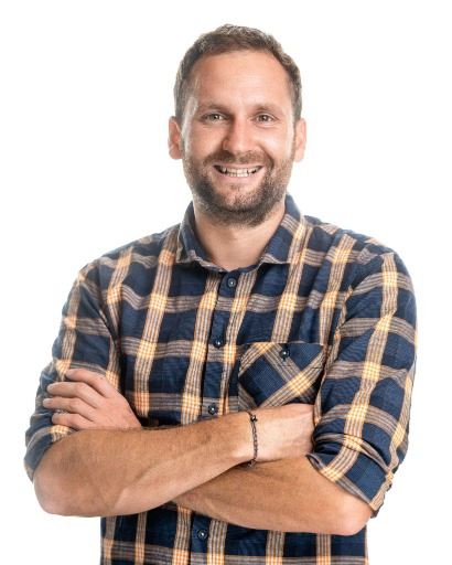 Mann in kariertem Hemd, verschränkt.